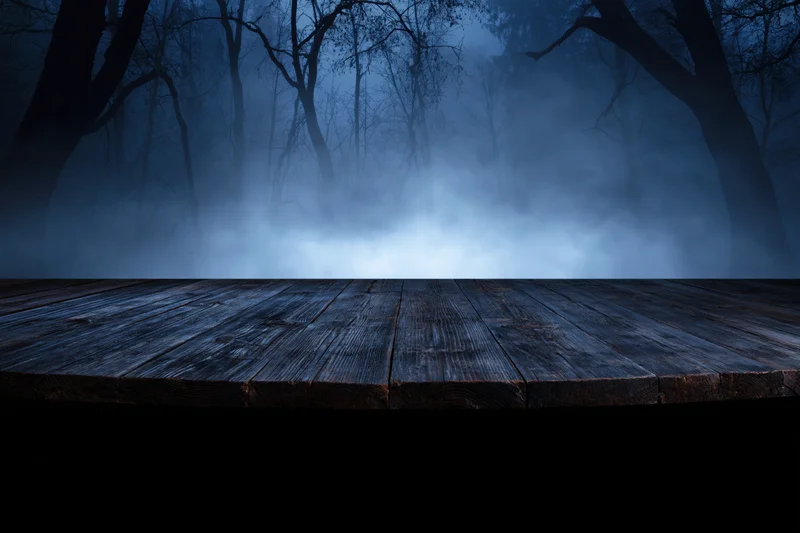 Weathered wooden plank table in a misty dark forest at night