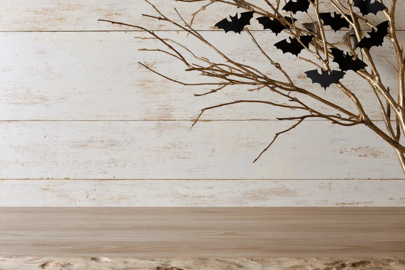 Golden branches with black bat cutouts on a rustic wooden tabletop for halloween decoration
