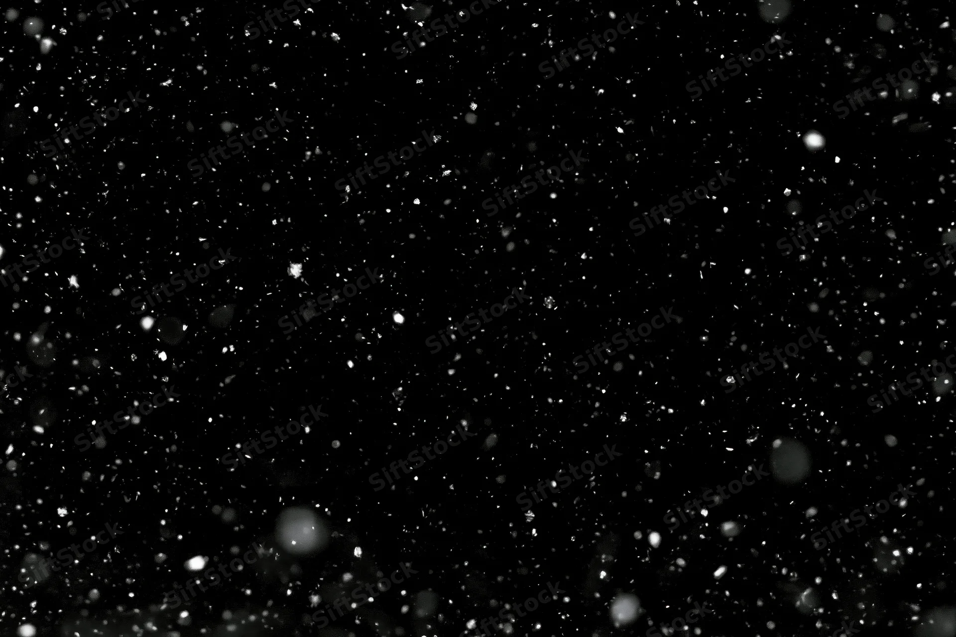 Snow particles falling midair against a black background