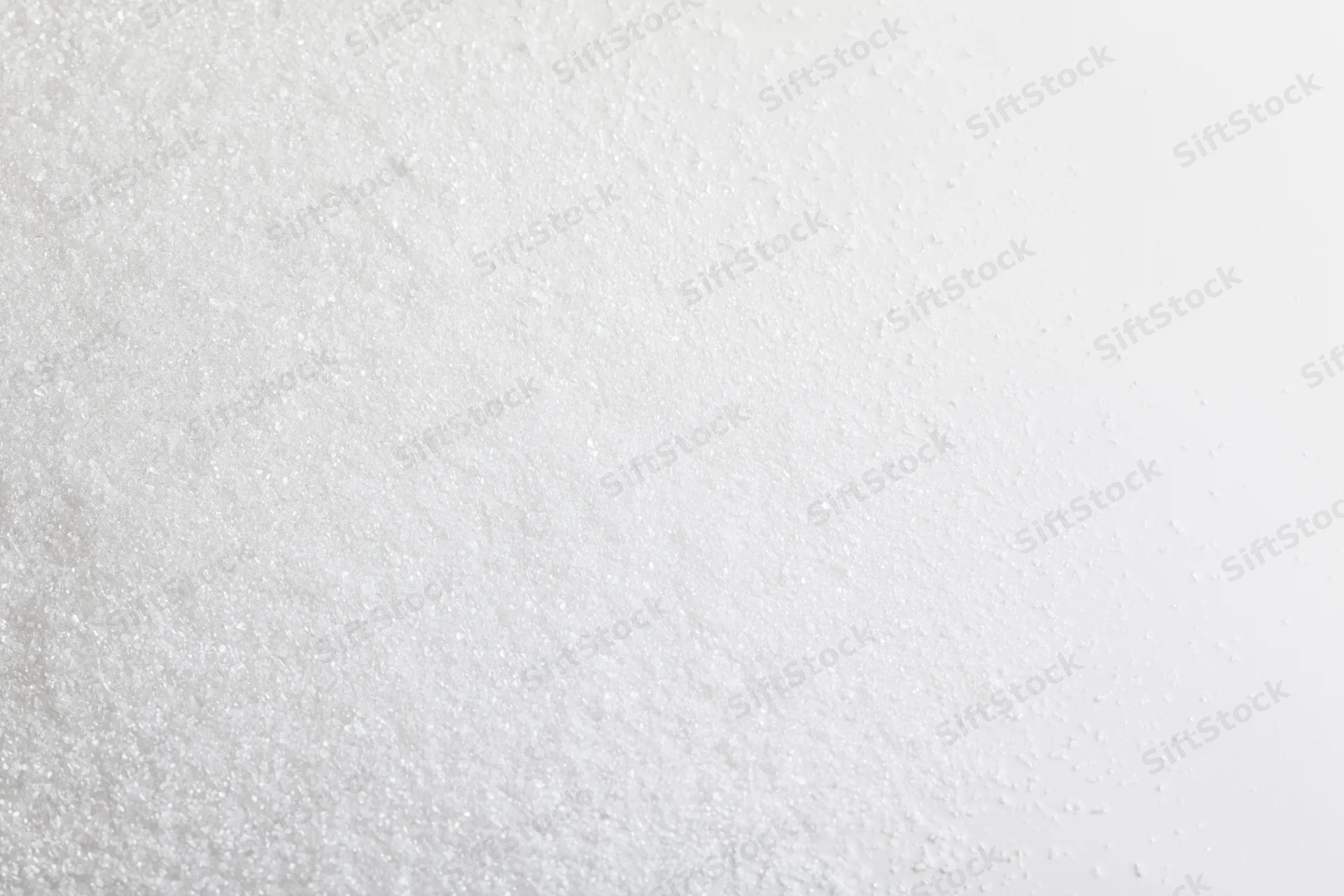 Fine white granular powder scattered unevenly across a plain surface