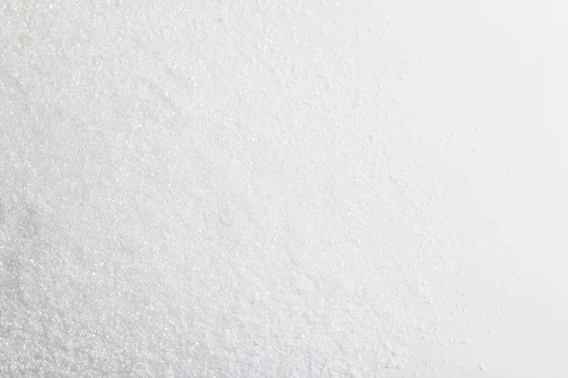 Fine white granular powder scattered unevenly across a plain surface
