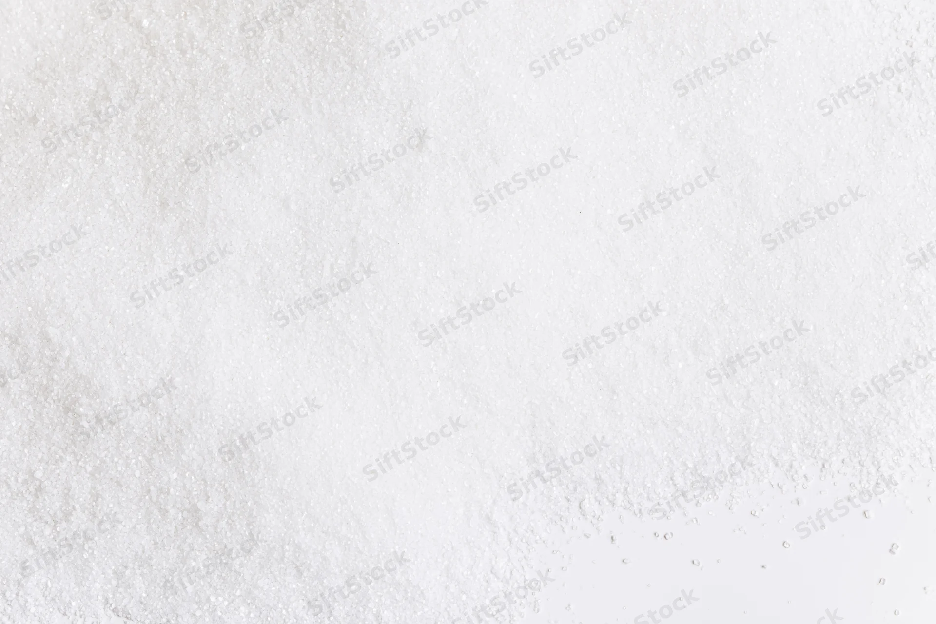 Fine white granular powder scattered unevenly across a smooth surface