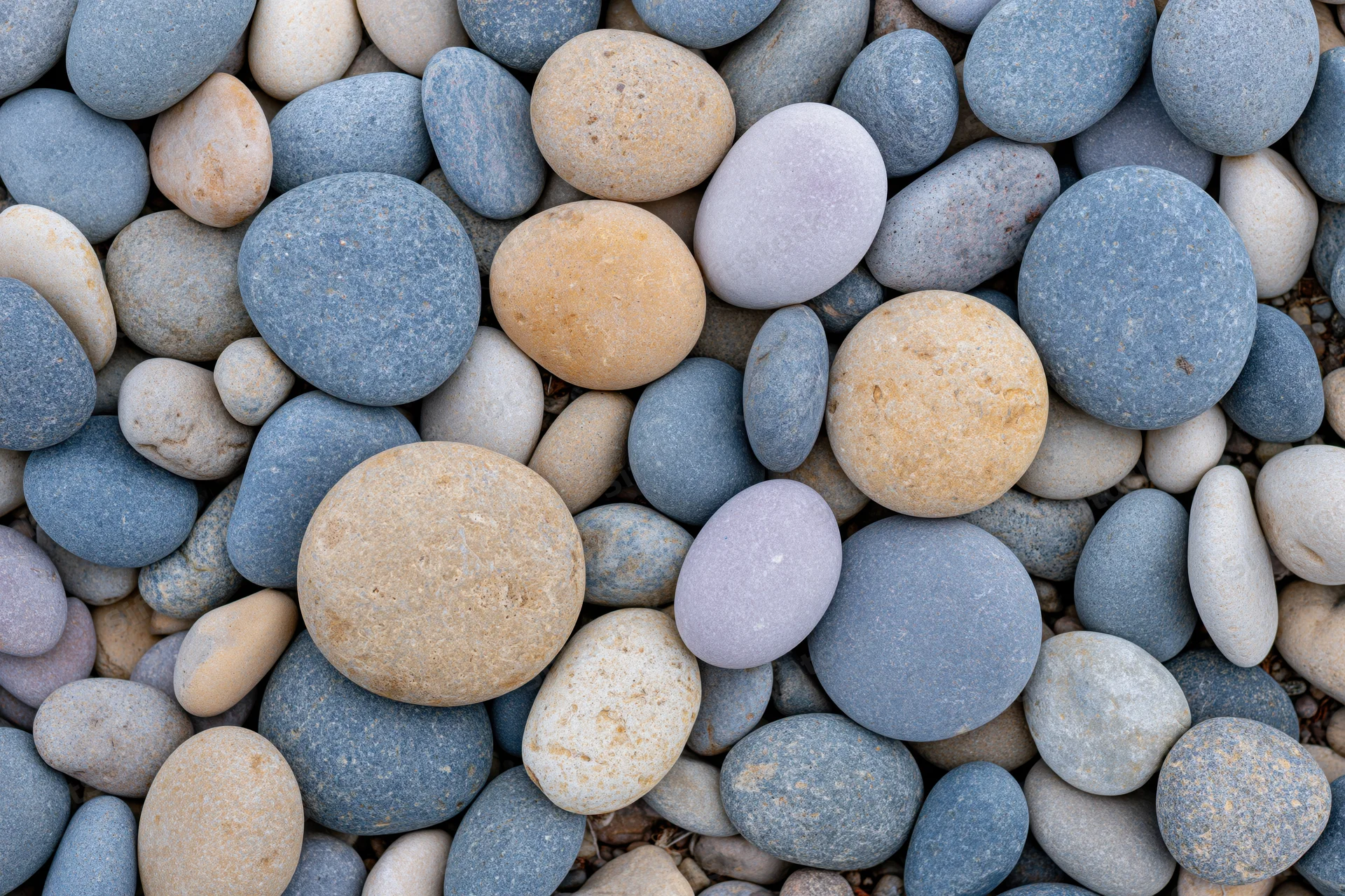 Smooth rounded pebbles in natural colors arranged in a flat lay close-up view