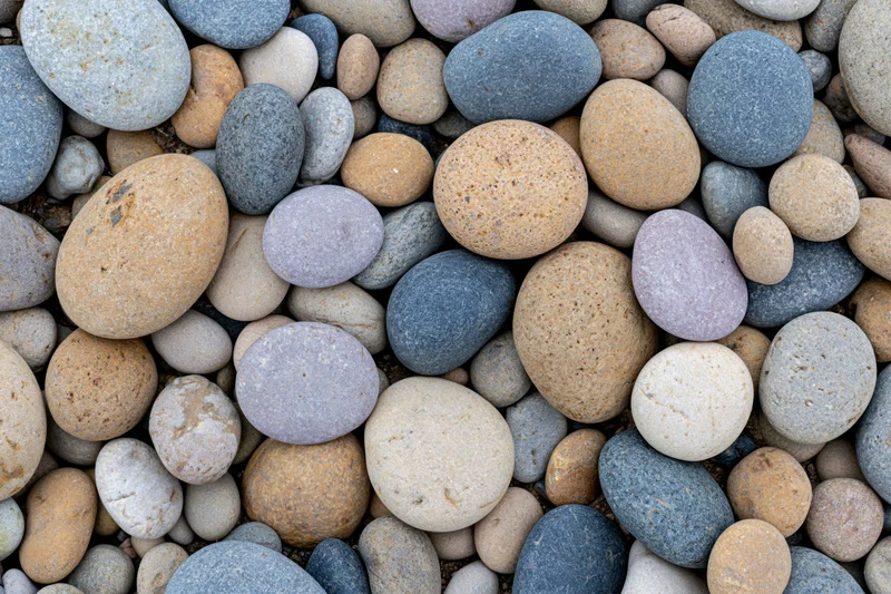 Smooth rounded river pebbles and beach stones arranged in a flat lay close-up view