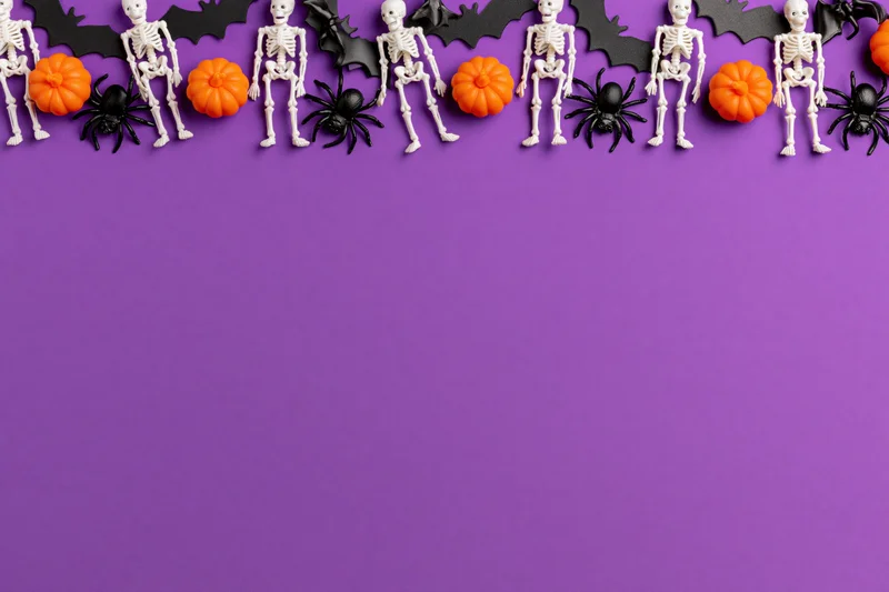 Halloween decorations arranged along the top edge on purple background
