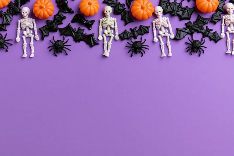 Halloween decorations arranged along the top edge on purple background with copyspace below