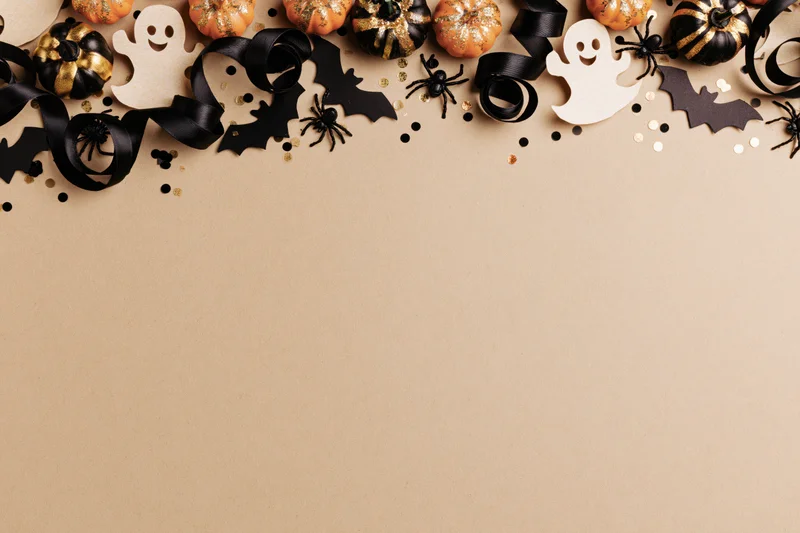 Halloween decorations arranged along the top edge of a beige surface with copyspace below