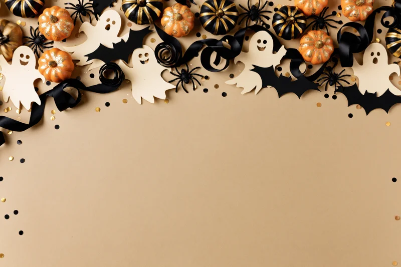 Halloween decorations arranged along the top edge on beige background with copyspace below