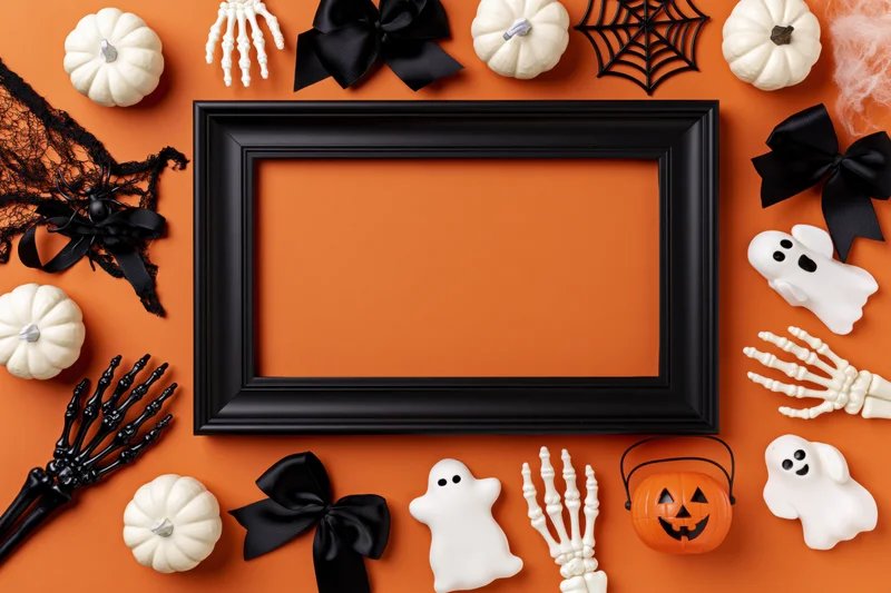 Black picture frame surrounded by halloween decorations on orange background