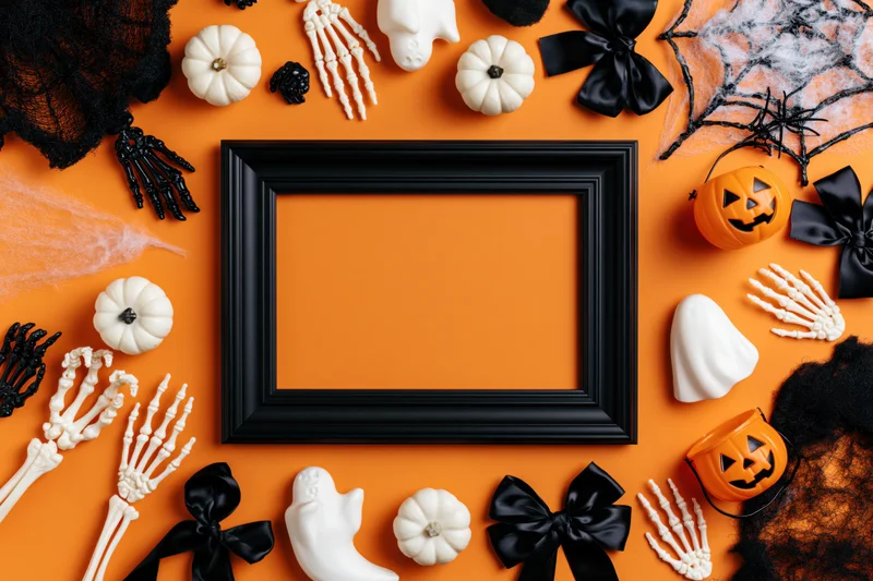 Halloween decorations arranged around a black frame on orange background