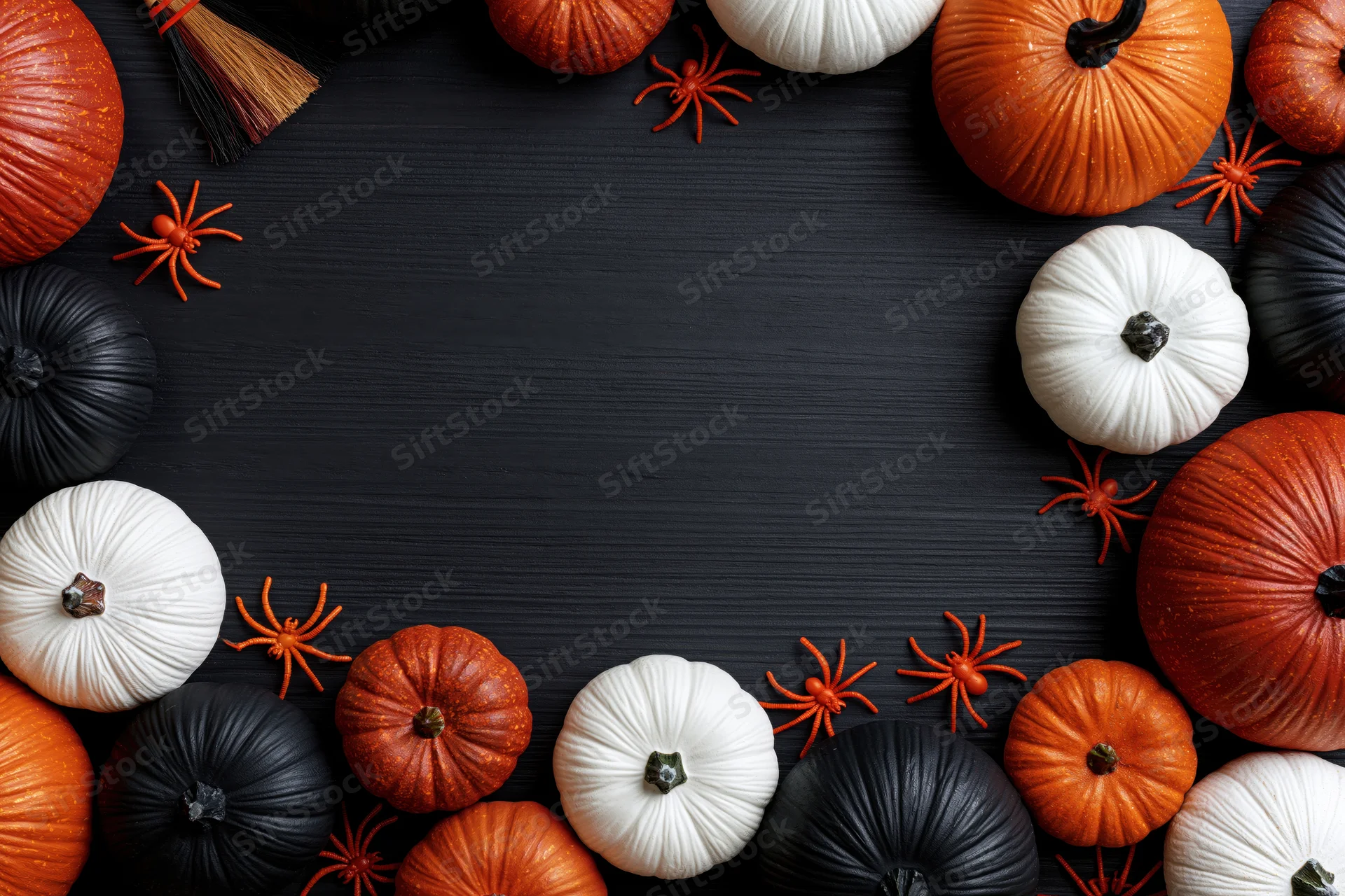 Halloween decorations arranged in a border around a dark wooden surface with copyspace in center