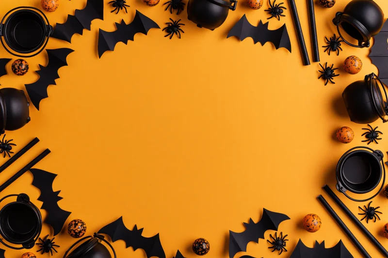 Halloween decorations arranged as a border frame on orange surface with copyspace