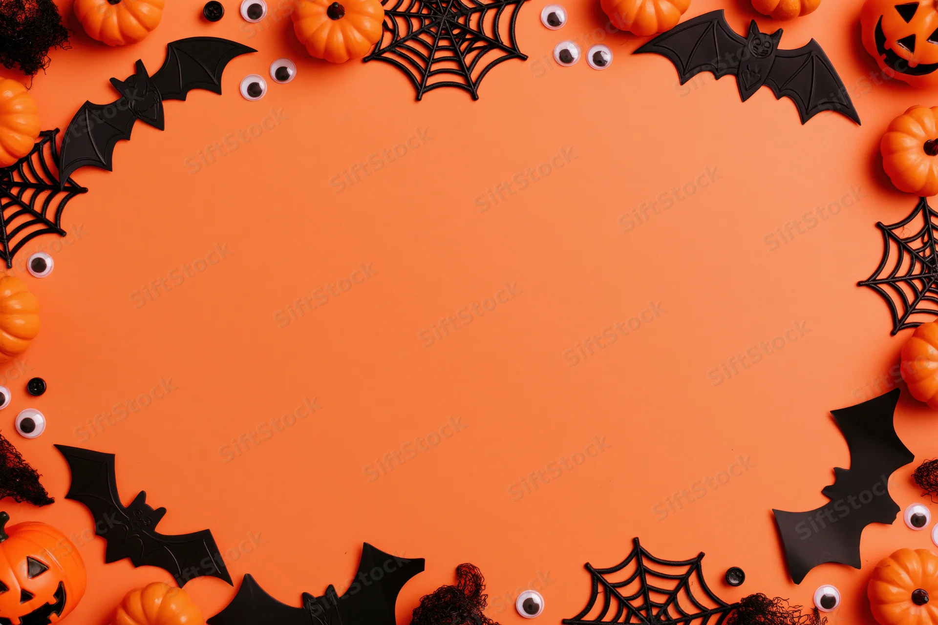 Halloween decorations arranged as a border frame on orange surface