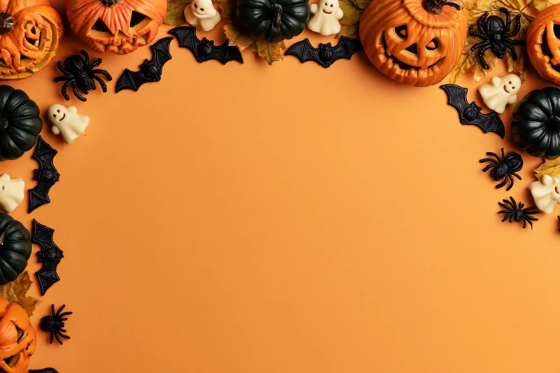 Halloween decorations arranged as a border frame on orange surface