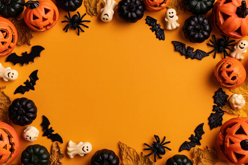 Halloween decorations arranged in a circular border frame on orange background with copyspace in center