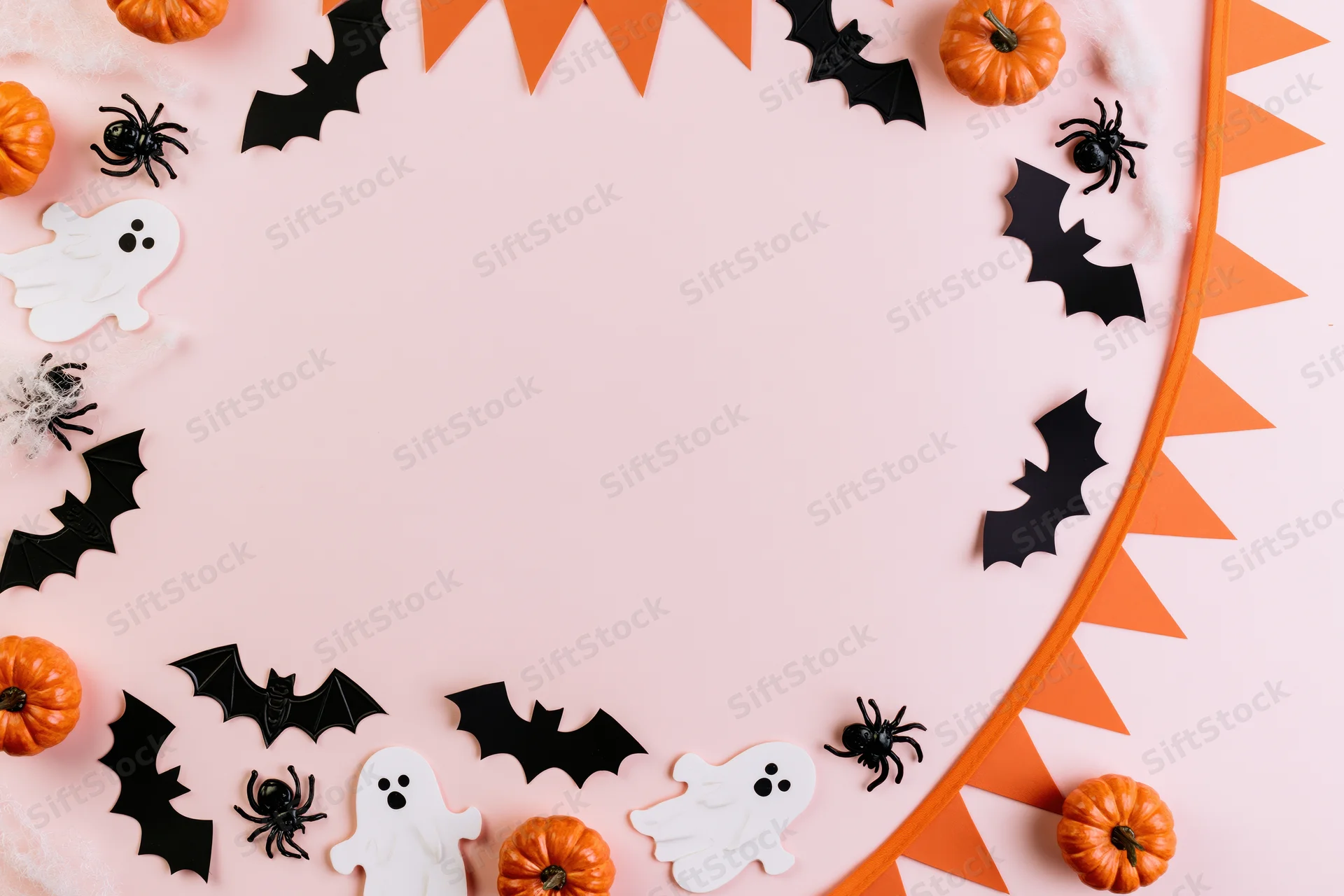 Halloween decorations arranged as a border frame on pink background with copyspace