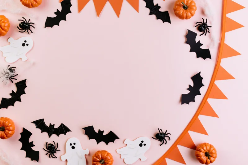 Halloween decorations arranged as a border frame on pink background with copyspace