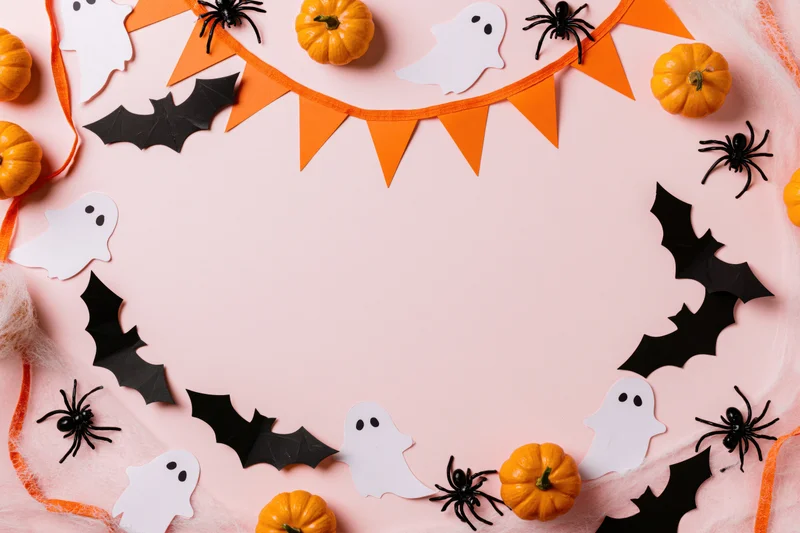 Halloween decorations arranged as a border frame on pink surface