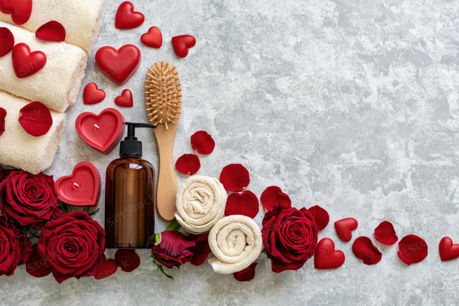 Valentines day spa items arranged along the bottom edge of a gray surface with copyspace