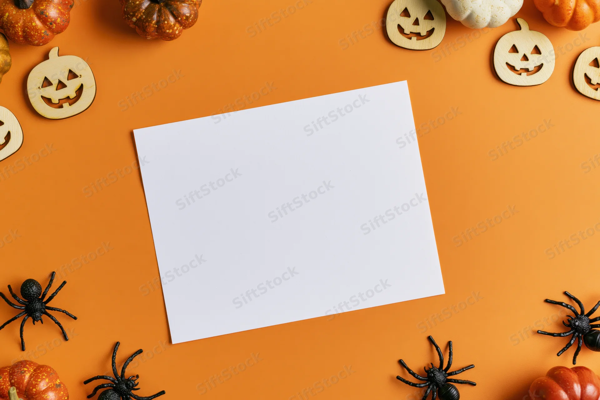 Blank white card centered on orange surface surrounded by halloween decorations