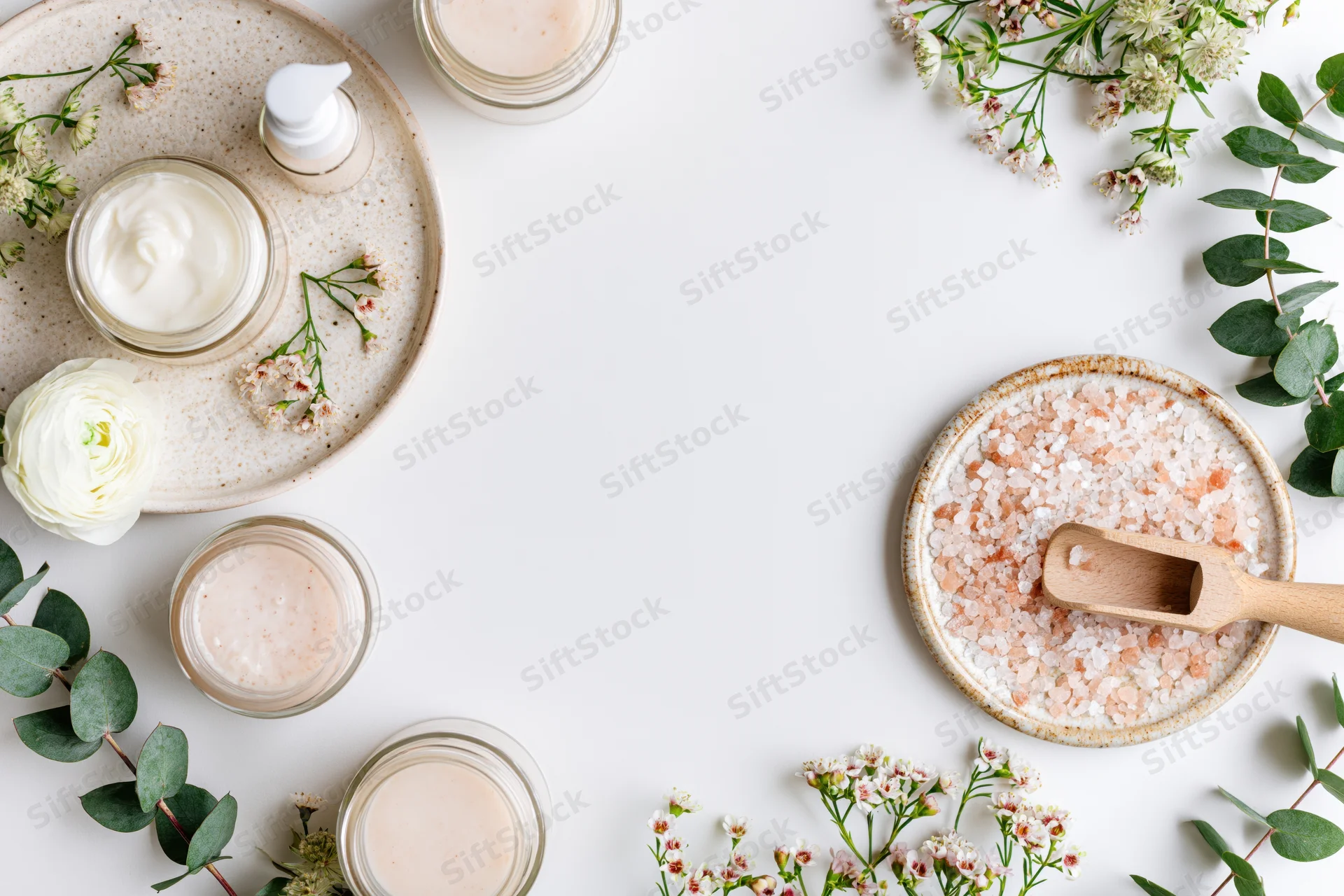 Skincare products and botanicals arranged in a flat lay on a white surface with copyspace
