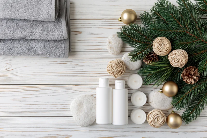 Spa and skincare products arranged with christmas decor on white wooden surface