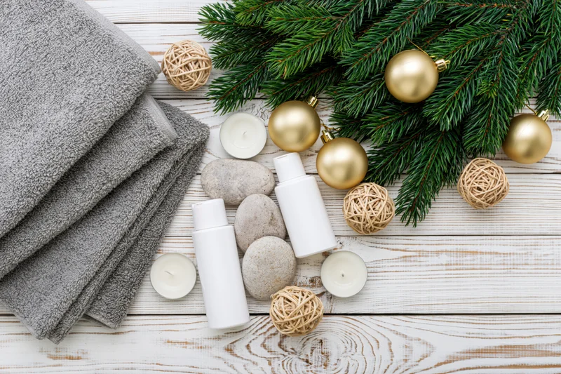 Spa and skincare products arranged with christmas decorations on a white wooden surface