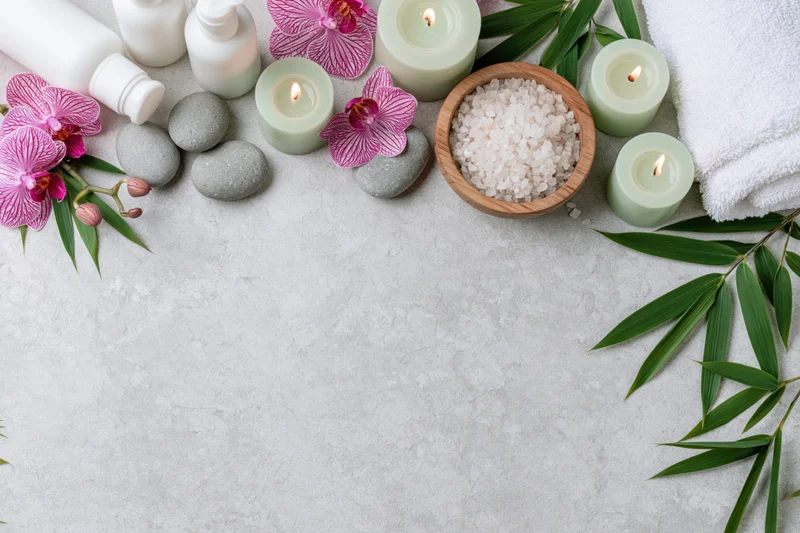 Spa wellness products arranged along top edge of textured surface with copyspace below