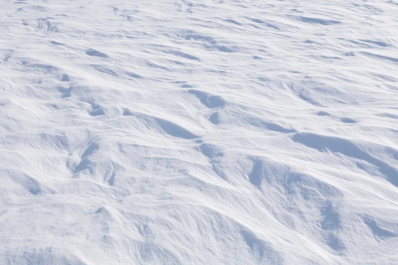 Wind-sculpted snow drifts across a flat open snowfield