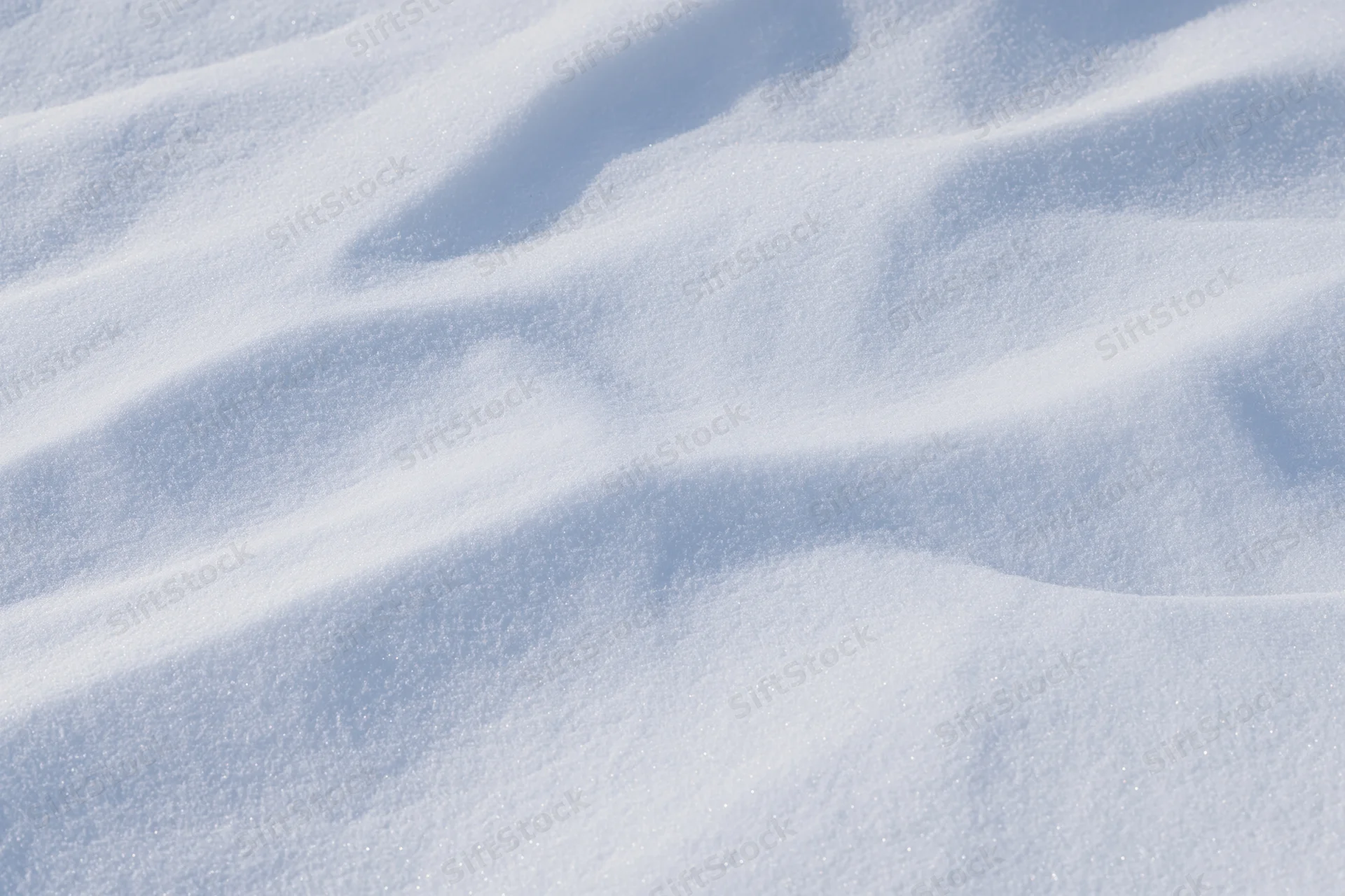 Undisturbed snow surface with gentle waves and sparkling texture filling the frame