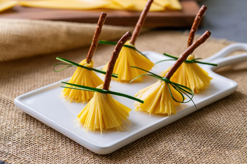 Cheese witch broom appetizers arranged on a white ceramic plate on burlap tablecloth
