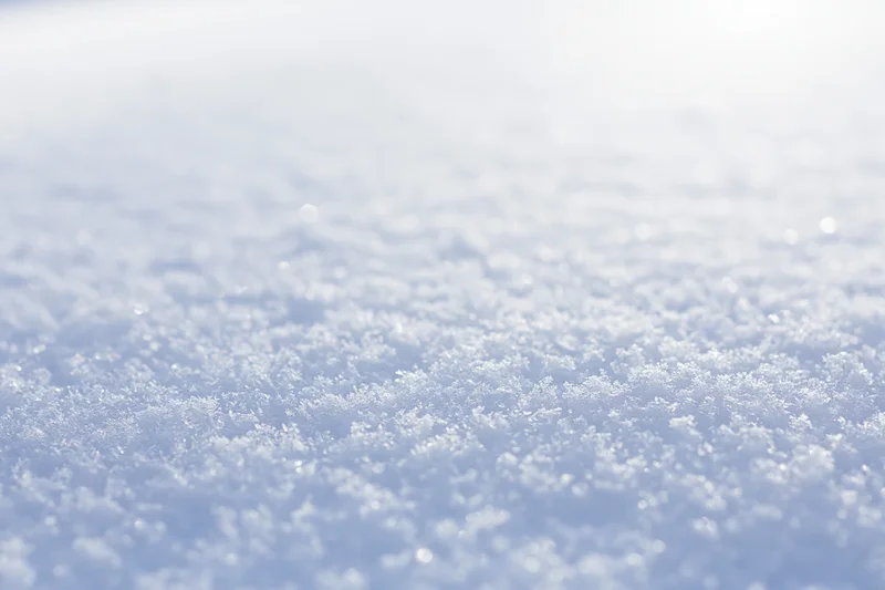 Closeup of fresh snow surface with visible ice crystals under bright light