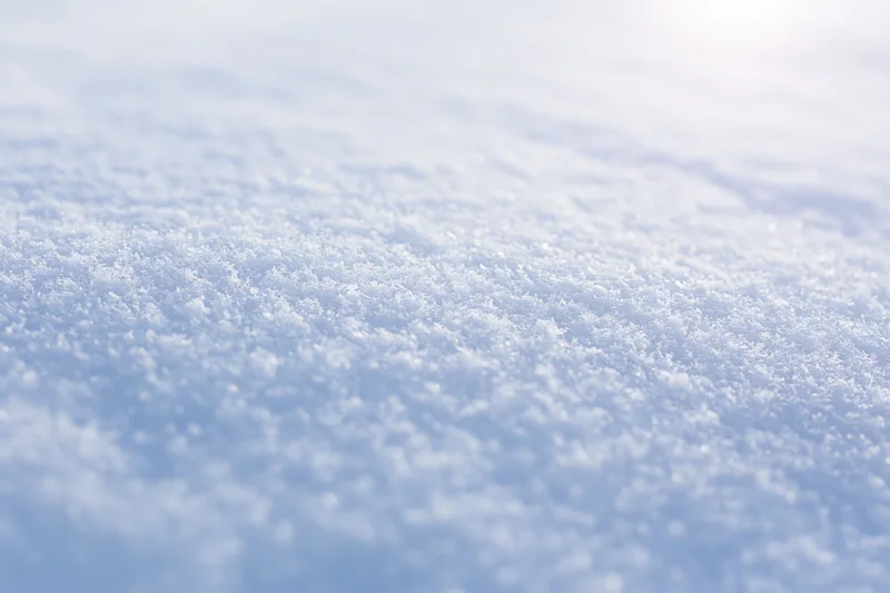 Closeup of fresh snow surface with visible individual snow crystals under bright light
