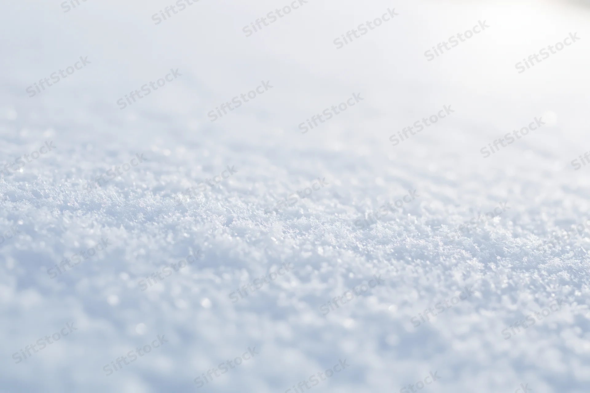 Closeup of fresh snow crystals on a sunlit surface with soft focus and bokeh background
