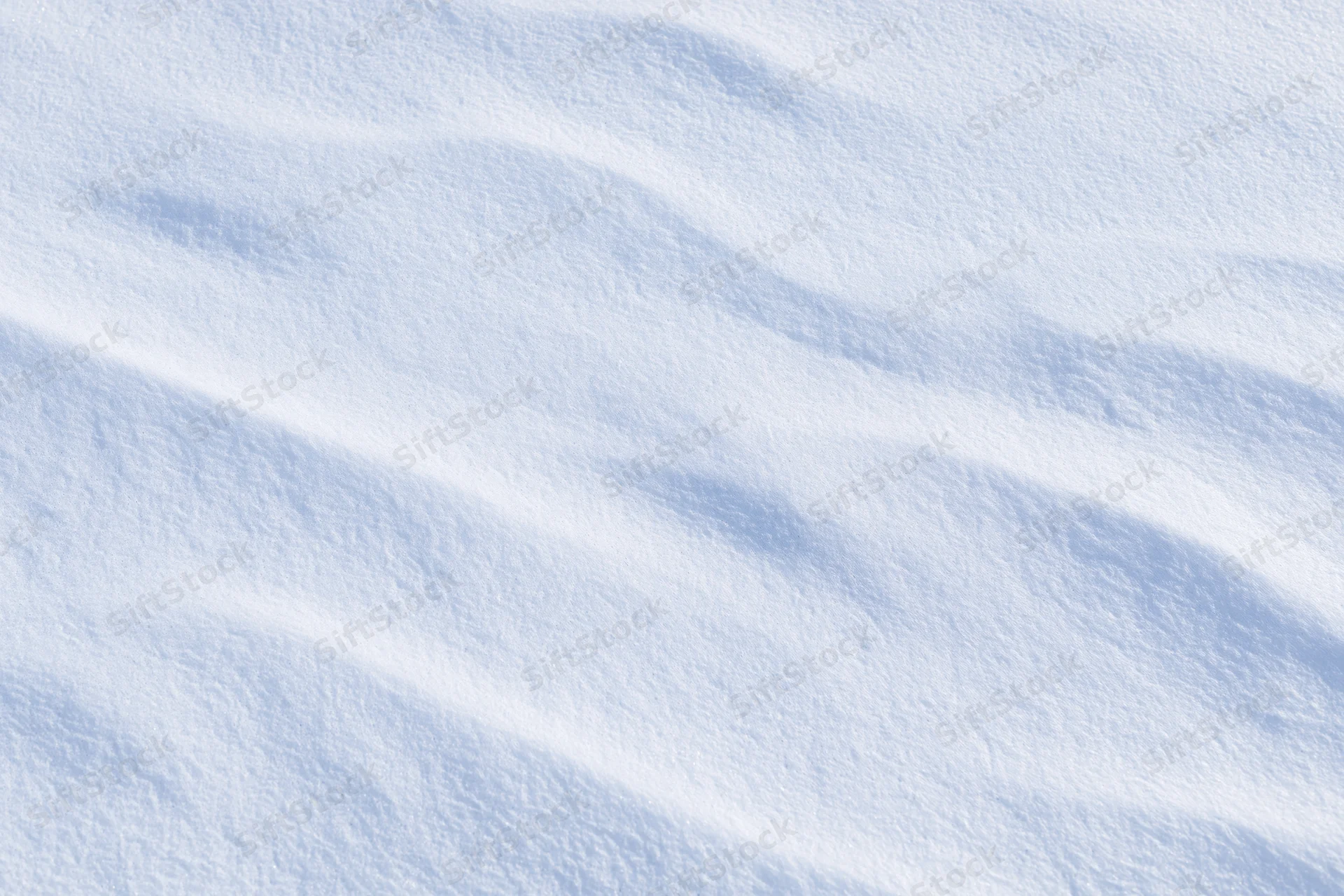 Undisturbed snow surface with soft ridges and gentle shadows filling the frame