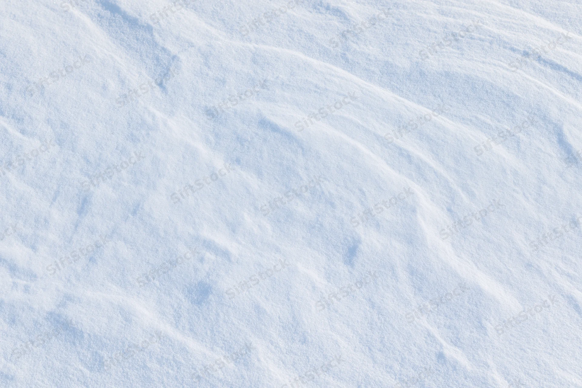 Undisturbed snow surface with soft ripples and texture filling the frame