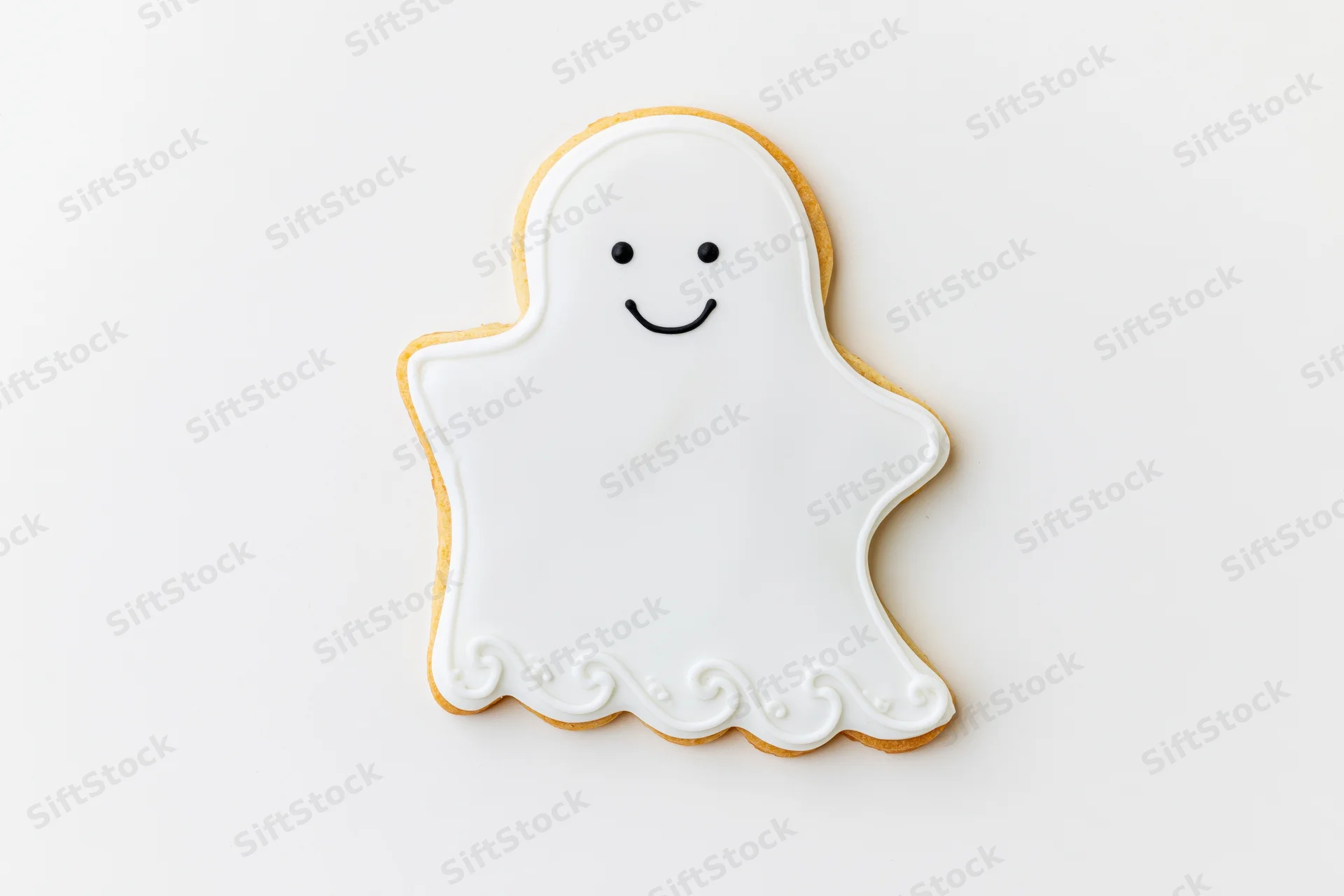 Ghost-shaped sugar cookie decorated with white icing and smiling face on white background