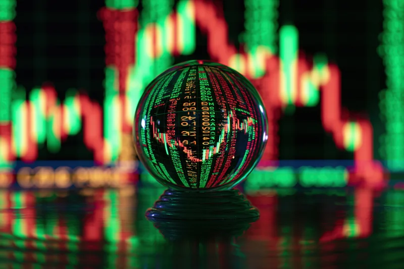 Glass crystal ball displaying financial data and stock market charts on a reflective dark surface