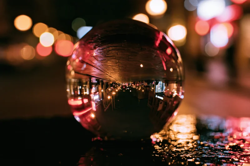 Crystal ball reflecting city lights at night on wet pavement