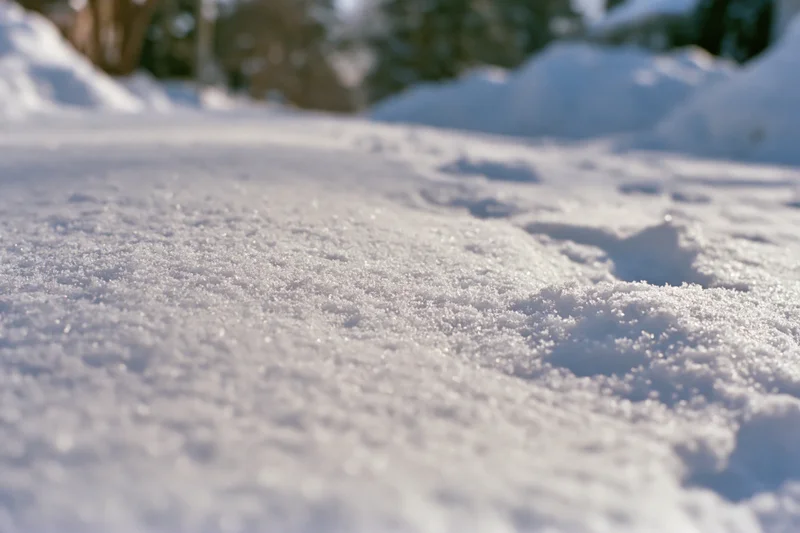 Closeup of fresh snow surface with granular texture and footprints on ground in winter landscape