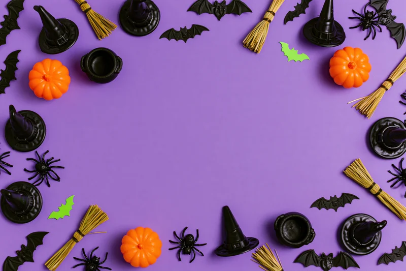 Halloween decorations arranged in a frame around a purple background with copyspace in center