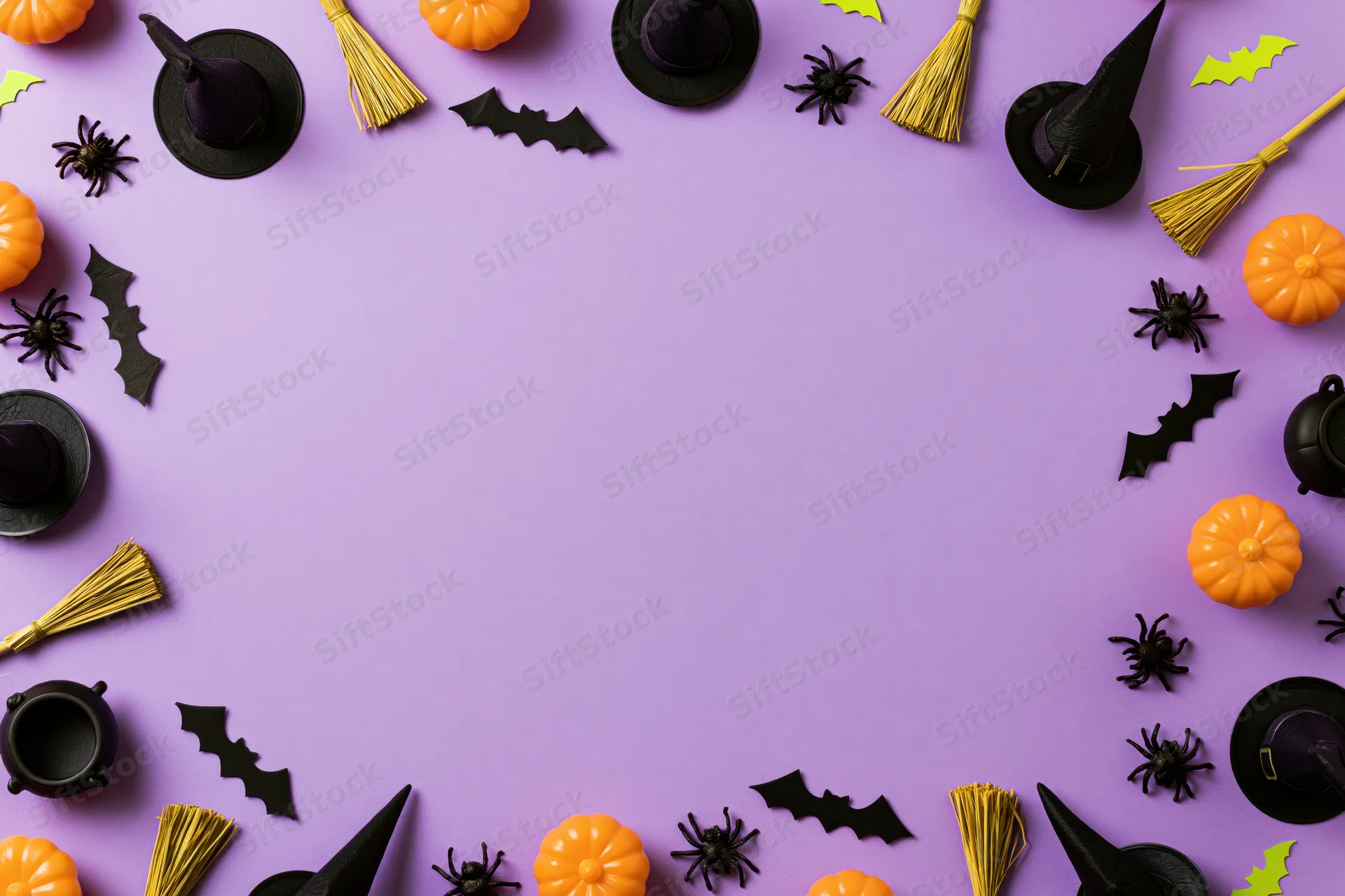 Halloween decorations arranged in a border around a purple surface with copyspace in center
