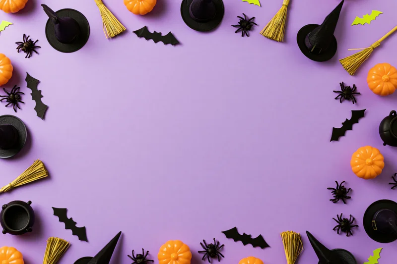 Halloween decorations arranged in a border around a purple surface with copyspace in center