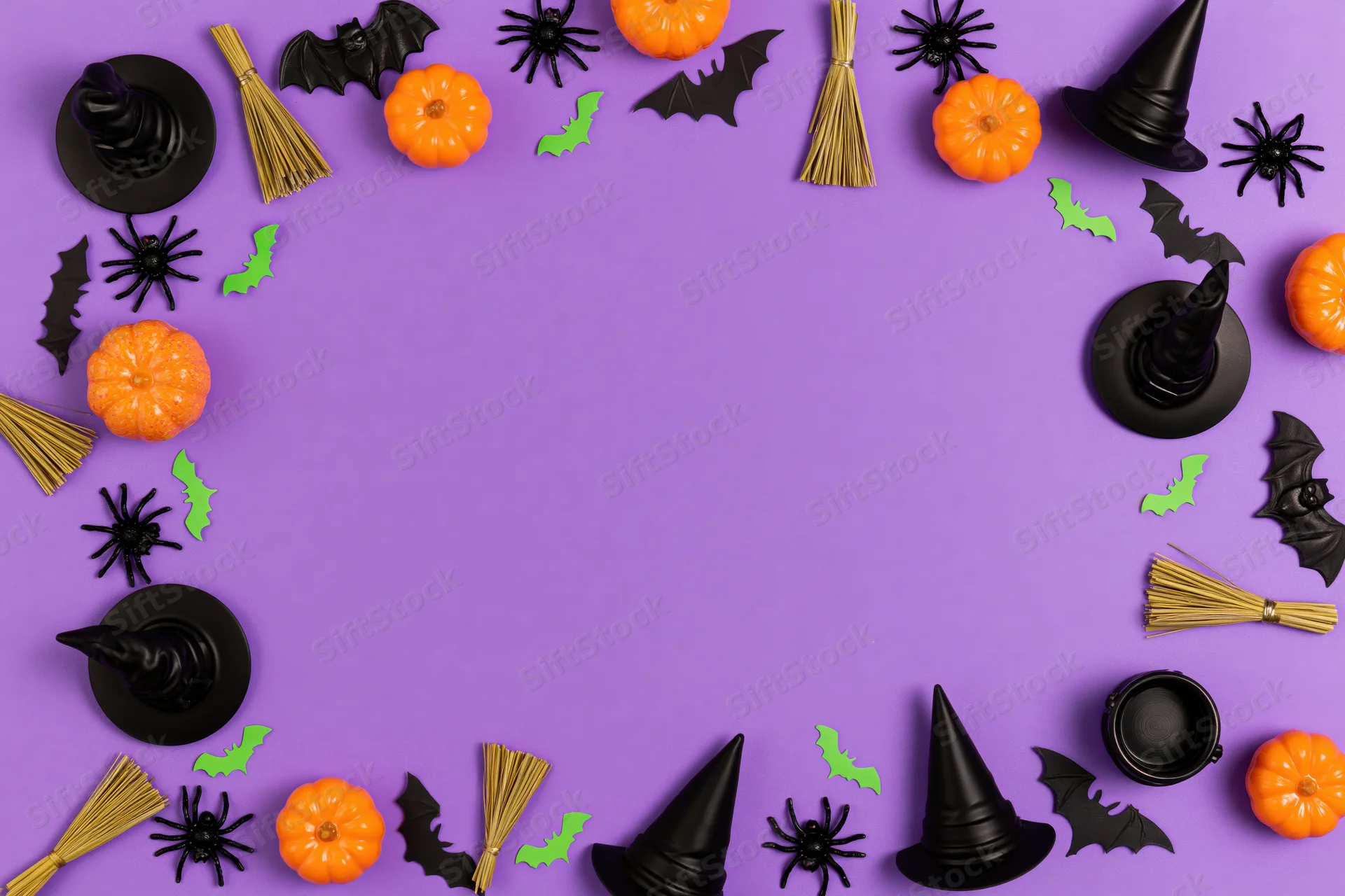 Halloween decorations arranged in a frame around copyspace on purple paper