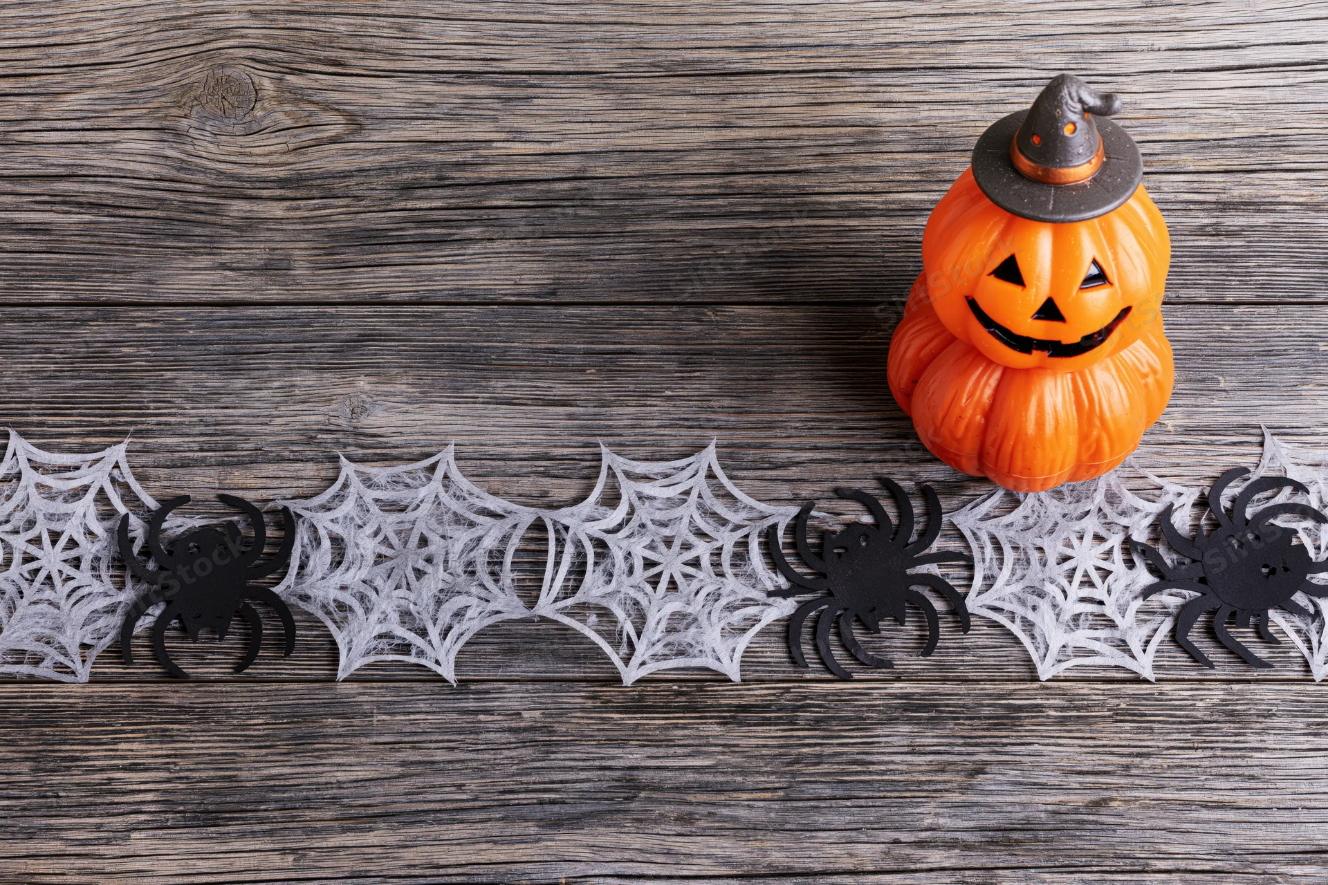Halloween decoration flat lay with paper spider and web cutouts on wooden surface