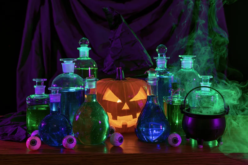 Witch's table with glowing potion bottles and jack-o'-lantern surrounded by smoke and eyeballs