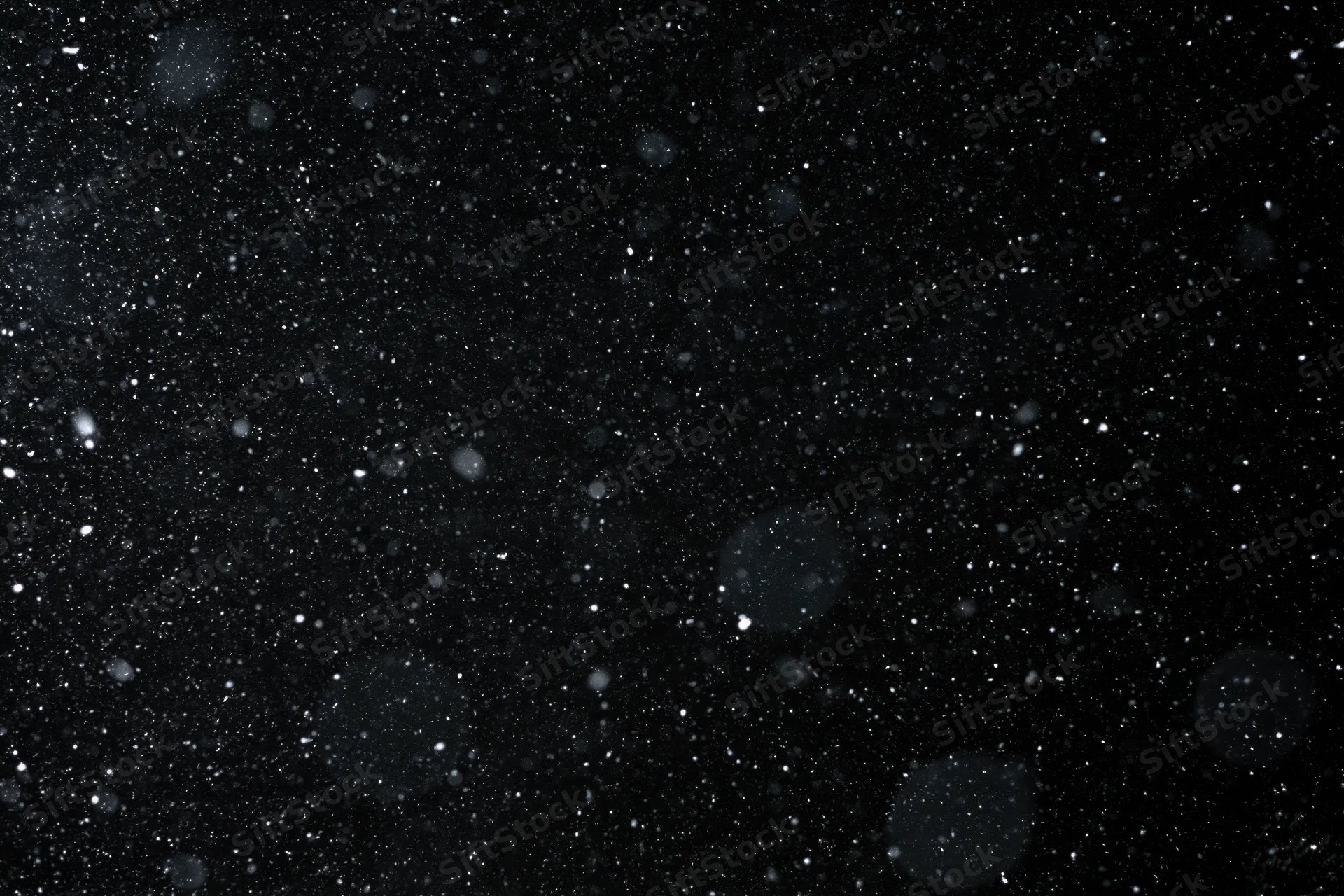 Heavy snowfall falling against a black night sky