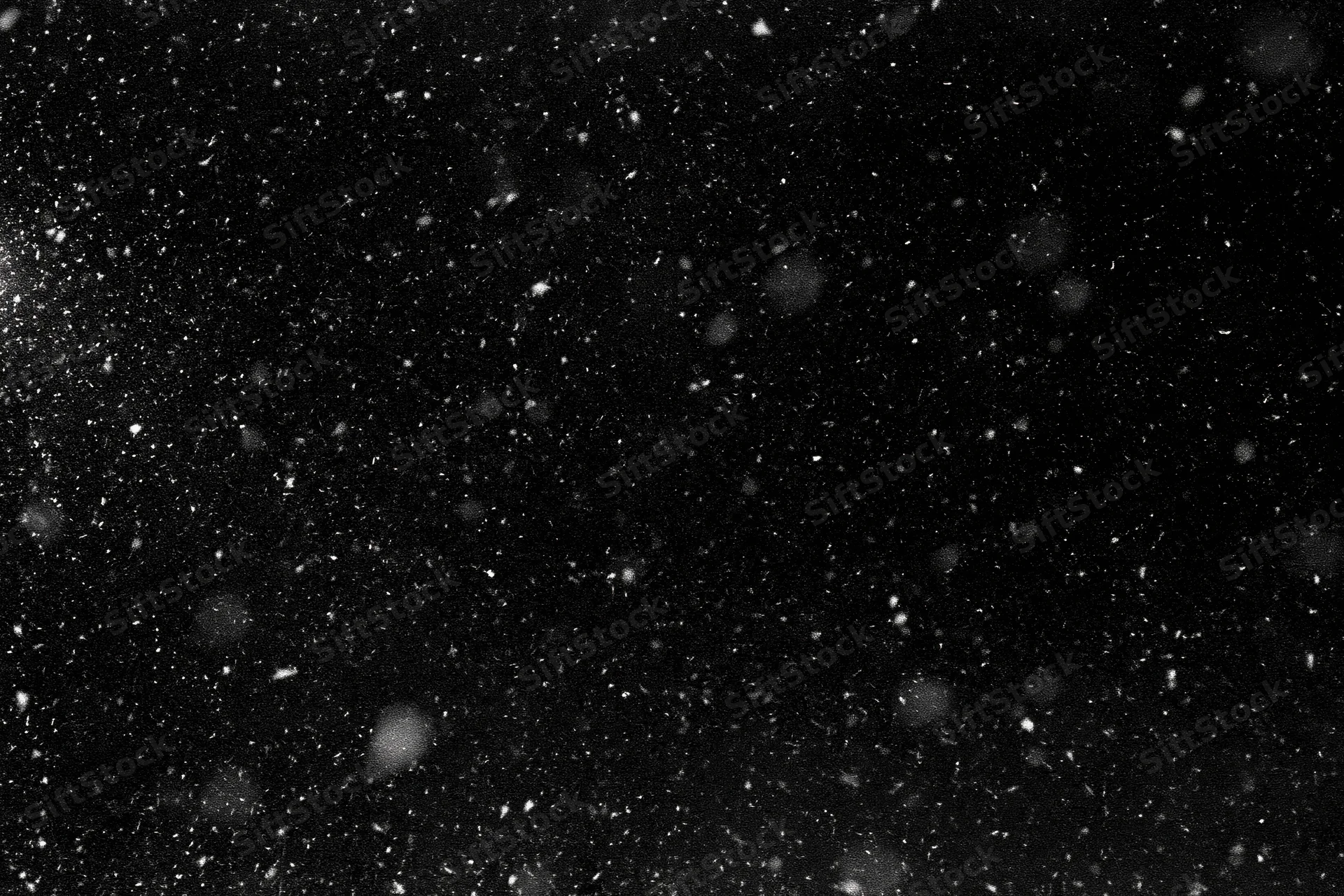 Snow falling densely against a black night sky