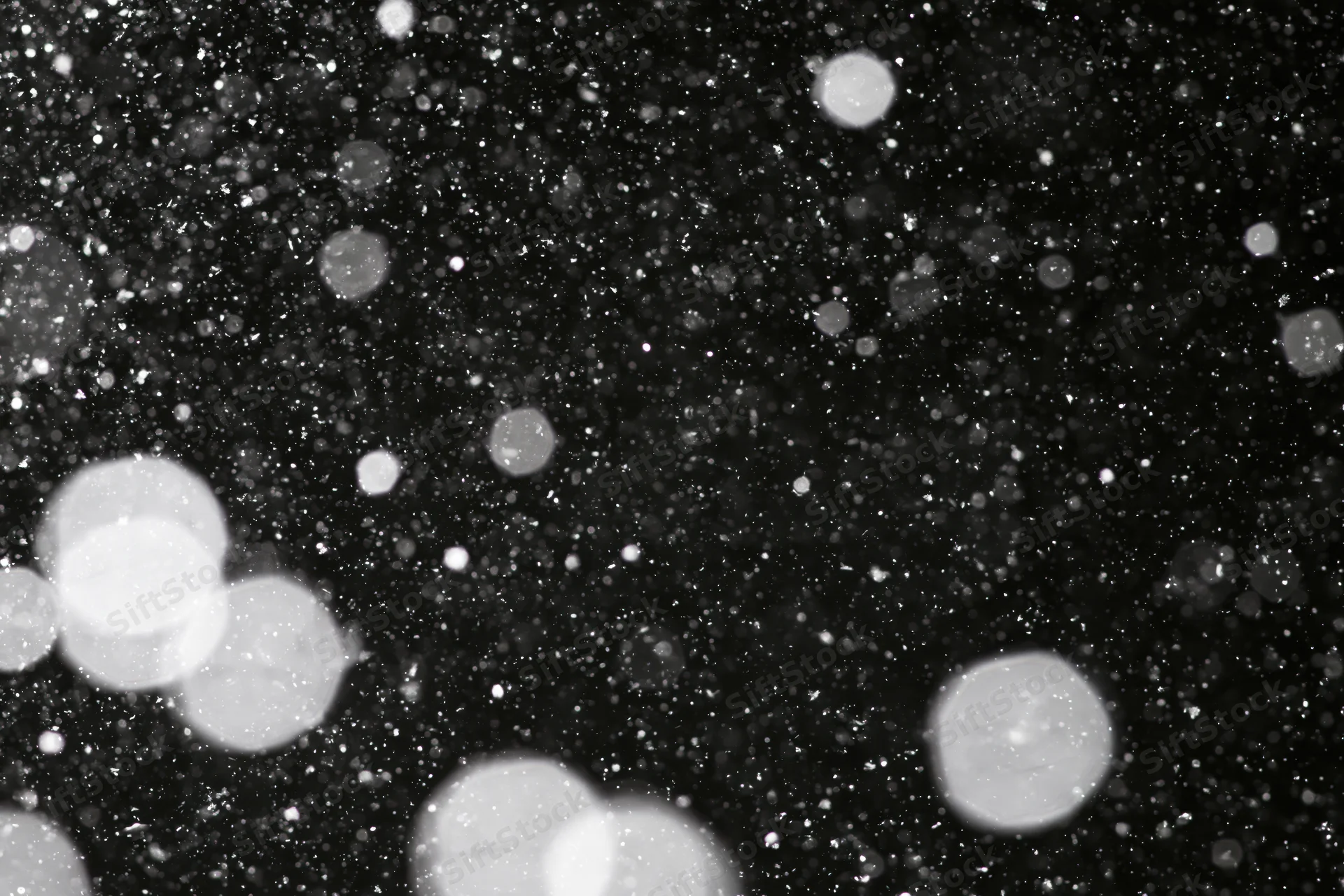 Snow falling against a black night sky