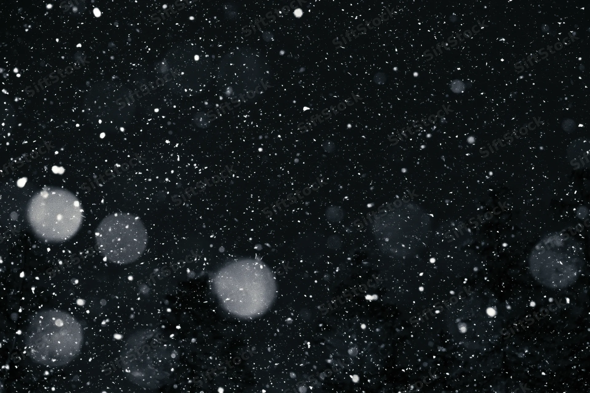 Snow falling heavily at night against a dark sky with blurred bokeh lights